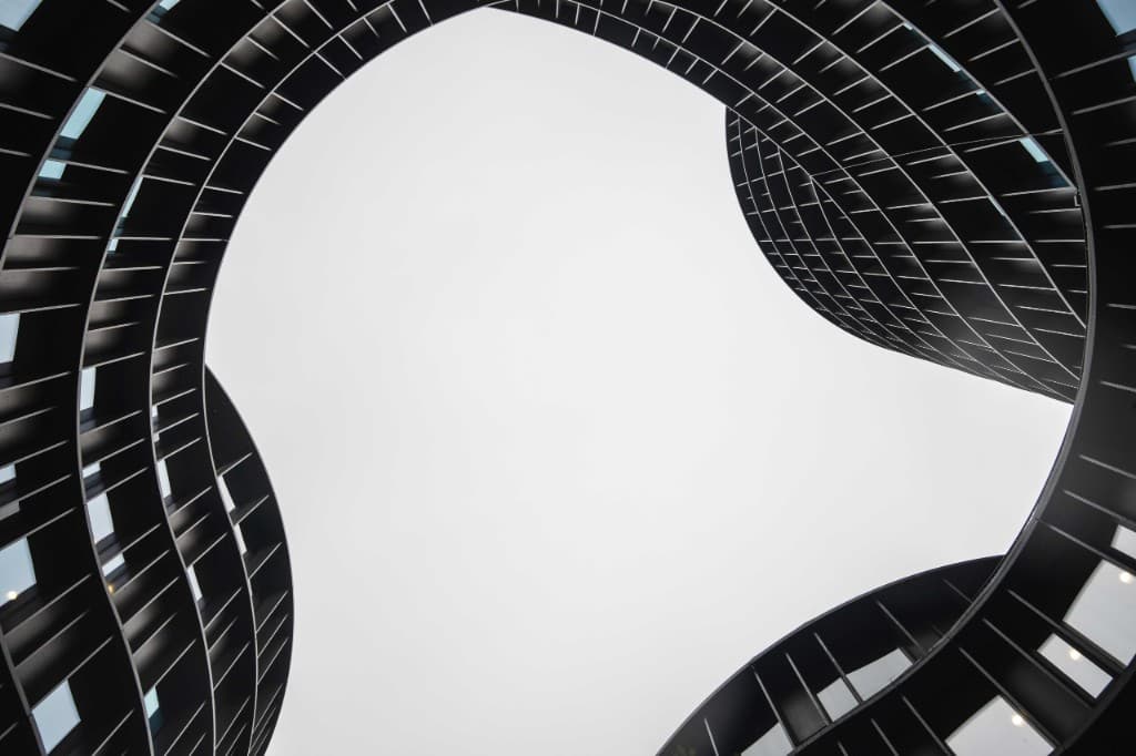 Low-angle view of modern curved towers framing a bright sky