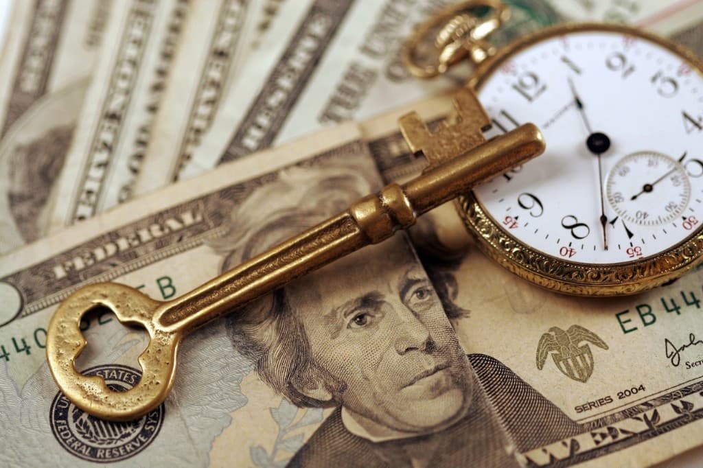Gold key and pocket watch on currency symbolising UAE Golden Visa and long-term residency