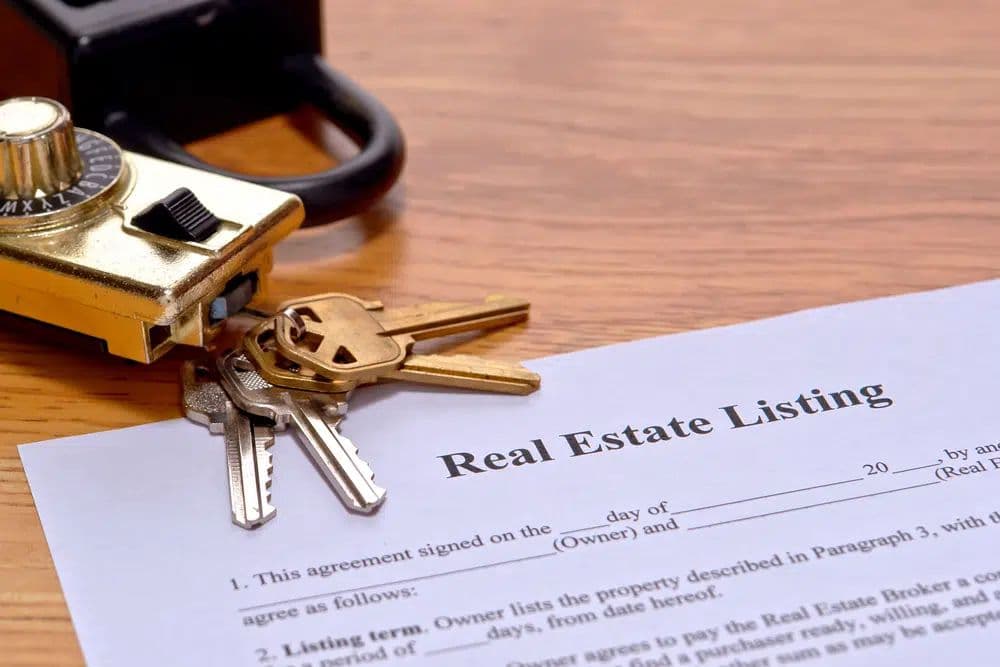 Real estate listing agreement with keys and lockbox on a wooden desk