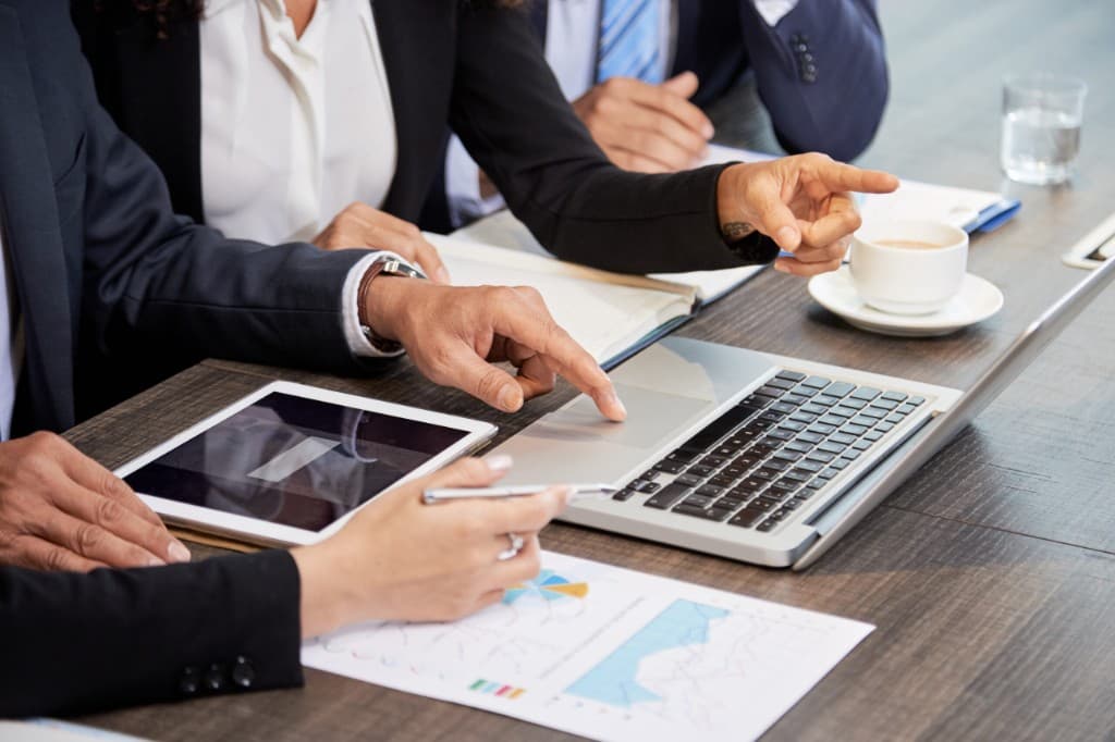 Business professionals reviewing property data on laptop and tablet at a meeting