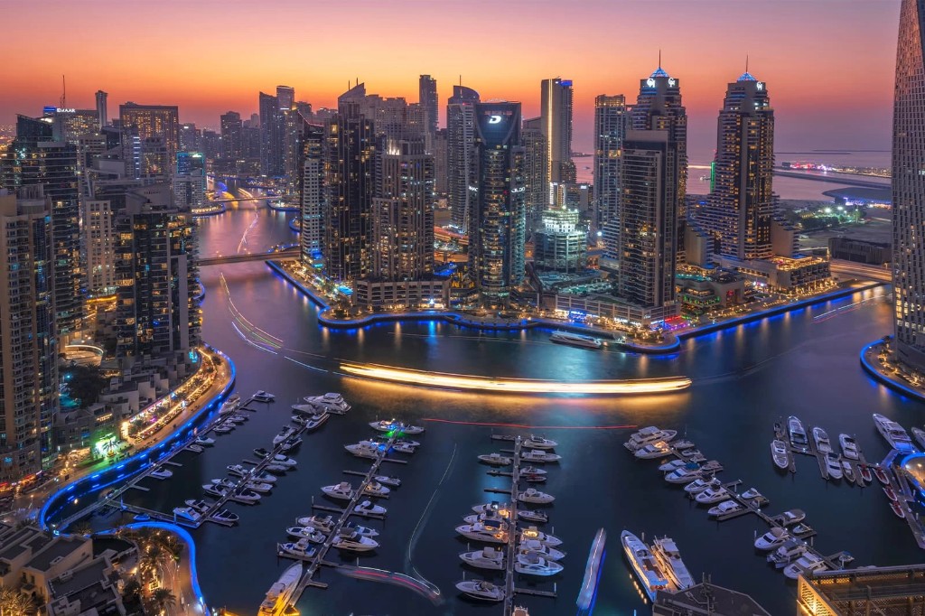 Aerial view of Dubai Marina at twilight with yachts and illuminated towers